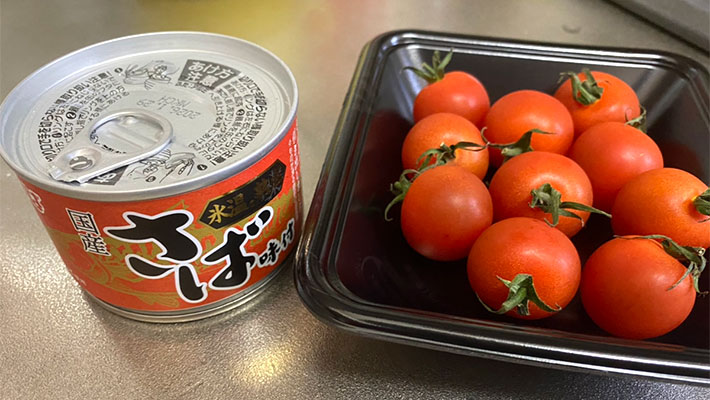 サバの味噌煮缶とミニトマトの写真